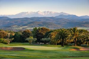 un campo de golf con palmeras y montañas al fondo en L'Heura, en Navata