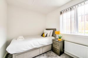 een witte slaapkamer met een bed en een raam bij 2-Bedroom Holiday Home With Private Garden & Parking in Edinburgh