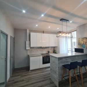 een keuken met witte kasten en een aanrecht met krukken bij Appartement très lumineux porte de Saint-Cloud - F3 avec suite parentale in Parijs