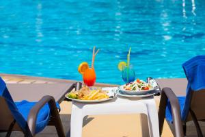 dos platos de comida en una mesa junto a una piscina en JP Pool & Apartments, en Kardamaina