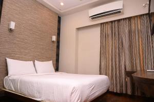 1 dormitorio con cama blanca y ventana en HOTEL CENTER POINT en Solapur