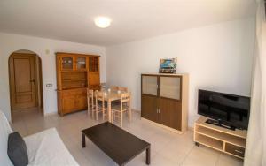 a living room with a television and a table at Primera línea con vistas al mar - Playamar 1022 ALBERT VILLAS in Alcossebre