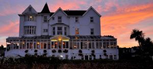 uma grande casa branca com um pôr-do-sol ao fundo em Marine Hotel em Paignton