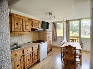 a kitchen with wooden cabinets and a table with a sink at Appartement Les Menuires, 2 pièces, 6 personnes - FR-1-178-325 in Les Menuires