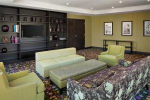a living room with a couch and chairs and a tv at The Limited Hotel in Charleston