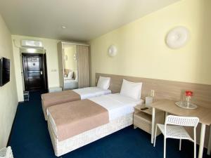 ソチにあるКурортный отель Coocooroozaの大きなベッドとテーブルが備わるホテルルームです。