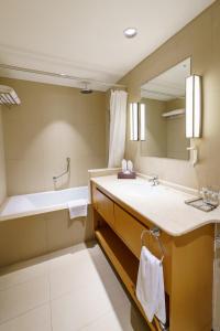 a bathroom with a sink and a tub and a mirror at Levatio Suites Muscat, a member of Radisson Individuals in Muscat