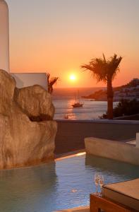 a pool with a sunset in the background at Anax Resort and Spa in Agios Ioannis Mykonos