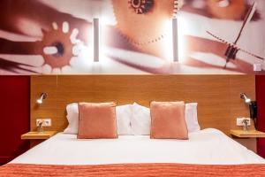 a bedroom with a large bed with two pillows at Hotel Ariane Montparnasse by Patrick Hayat in Paris