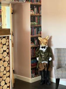 Uma raposa empalhada está em frente a uma estante de livros. em Cosy country cottage in rural location em Moffat