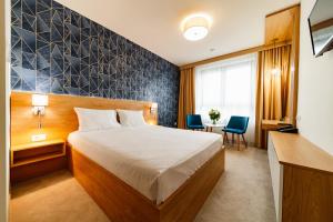 a hotel room with a bed and a table and chairs at Hotel Küküllő - Târnava in Odorheiu Secuiesc