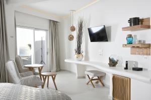 a white bedroom with a bed and a desk and chairs at Anax Resort and Spa in Agios Ioannis Mykonos