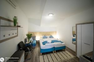Schlafzimmer mit einem Bett mit blauen und weißen Kissen in der Unterkunft Panoráma Birtok - Wellness Panzió, Konferencia és Rendezvényközpont in Győrújbarát