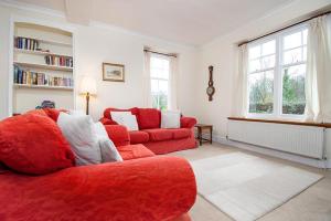 a living room with a red couch and a red chair at Rhos Cottage in Conwy