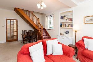 a living room with a red couch and a staircase at Rhos Cottage in Conwy