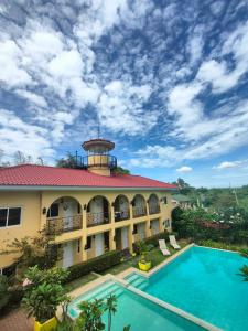 a building with a swimming pool and a tower at Villa Del Faro in Batangas City