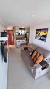 ein Wohnzimmer mit einem braunen Sofa und einer Küche in der Unterkunft Marina Bezerril - Cobertura Lemon Flat - A melhor de Ponta Negra in Natal