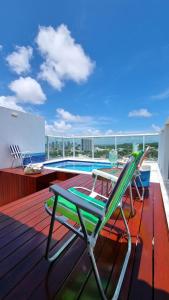 a deck with a chair and a swimming pool at Cobertura mobiliada Ponta Negra in Natal