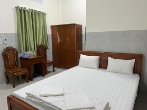 Schlafzimmer mit einem Bett, einem Schreibtisch und einem Stuhl in der Unterkunft Khách sạn Hoàng Gia - TT Lai Vung in Lai Vung