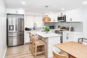 cocina con armarios blancos y mesa de madera en Hawaii Dream Escape! Steps from the Sand, en Hauula