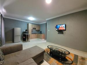 a living room with a couch and a tv on a wall at Khayalami Hotel - Standerton in Standerton