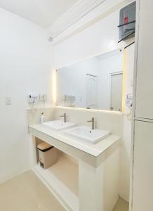 a white bathroom with two sinks and a mirror at NomadsMNL Hostel in Manila