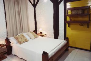 1 dormitorio con cama blanca y pared amarilla en Sítio Urbano a apenas 1,5 km do centro, en Blumenau