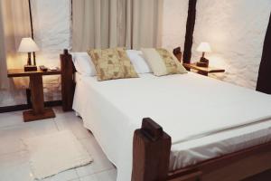 a bedroom with a large white bed with two lamps at Sítio Urbano a apenas 1,5 km do centro in Blumenau