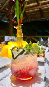 a drink in a glass on a table with a vase at The Hawk's Nest Resort in Sabang