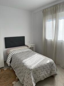 a white bedroom with a bed and a window at HUELIN PLAYA in Málaga
