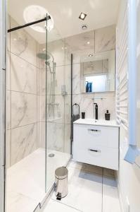 a white bathroom with a shower and a sink at Black and White cosy in Sedan