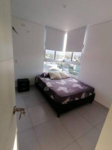 a small bed in a room with a window at Apartamento en Santa Marta, Rodadero Jacuzzi y Sauna in Gaira +25 photos