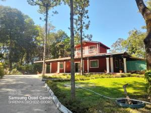 Uma casa com uma mangueira à frente. em Shrenya Orchidz-Coorg Nature Stay em Madikeri