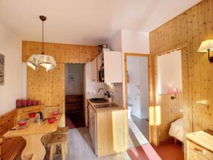 cocina con paredes de madera, mesa y barra en Appartement Les Menuires, 2 pièces, 6 personnes - FR-1-178-169, en Les Menuires