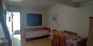 1 dormitorio con cama, mesa y TV en Aluguéis Cleusa, en Torres