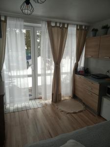GrywałdにあるWypoczynek u Gosiのベッドルーム1室(白いカーテン付きの大きな窓付)
