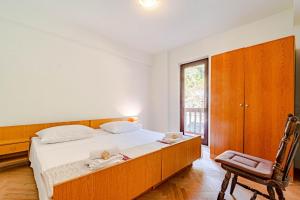 a bedroom with a bed and a chair and a window at Apartmani Antula in Prigradica