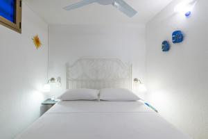 a white bed in a white room with two pillows at Domus Luna Apartment with sea view Villasimius in Villasimius