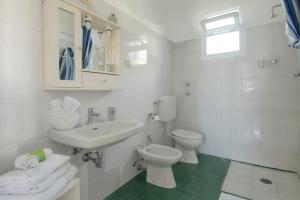 uma casa de banho branca com um lavatório e um WC em Rusticano B&B em Ischia