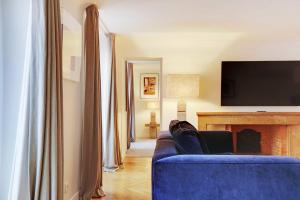 un soggiorno con divano blu e TV di Amazing apartment 2BR4P avenue Montaigne Triangle d'Or a Parigi