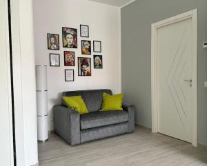 una sala de estar con una silla gris y cuadros en la pared en Simply House Civitavecchia en Civitavecchia