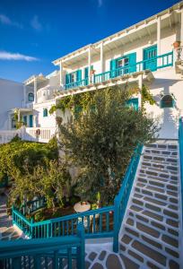 een groot wit gebouw met blauwe balkons en bomen bij Pension Marias in Mykonos-stad