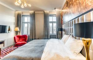 a bedroom with a large bed and a red chair at Grand Poet Hotel and SPA by Semarah in Rīga