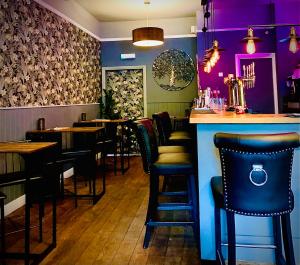 a bar with black chairs and purple walls in a restaurant at The Capon Tree Town House in Jedburgh