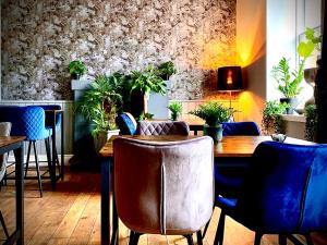 a dining room with a wooden table and blue chairs at The Capon Tree Town House in Jedburgh