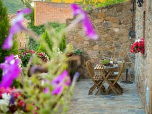 a patio with a table and chairs and a stone wall at Can Toni Vell Espinelves in Espinelvas