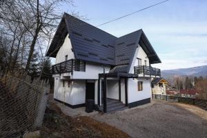 een klein wit huis met een zwart dak bij Pensiunea CityView in Câmpulung Moldovenesc