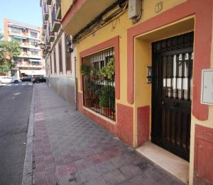 una acera vacía al lado de un edificio con una puerta en RentalSevilla Cool flat in Triana with parking., en Sevilla