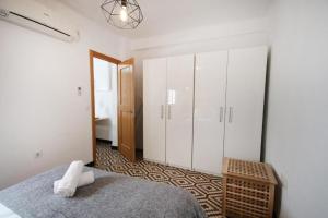 1 dormitorio con cama, armarios blancos y espejo en RentalSevilla Cool flat in Triana with parking., en Sevilla
