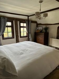 a large white bed in a bedroom with windows at Arms Cottage in Bridge